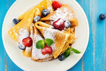 Crepes with jam, berries and sugar powder. Homemade pancakes, delicious breakfast