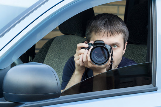 A man is taking photo someone or something from an open car window