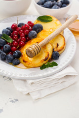 Cottage cheese pancakes syrniki with berries and honey on white background. Space for text