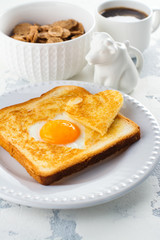 Breakfast for Valentines day: toast with heart shaped egg, muesli and coffee on white concrete table. Space for text