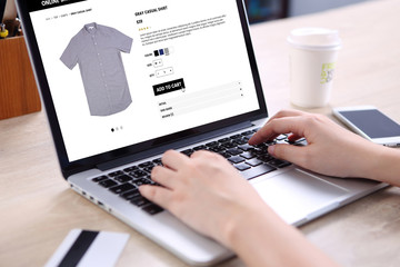 People buying casual shirt on ecommerce website with smart phone, credit card and coffee on wooden...