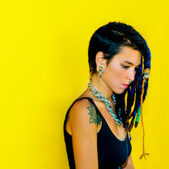 Cool Colombia girl with dreadlocks and piercings over colorful yellow wall
