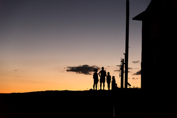 Silhouette of a family on top of a mountain while the sun is rising.
