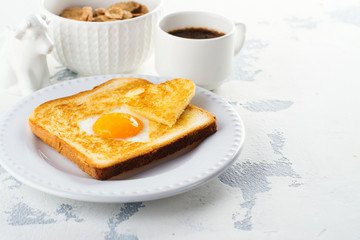Breakfast for Valentines day: toast with heart shaped egg, muesli and coffee on white concrete table. Space for text