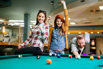 Fototapeta premium Happy friends enjoying playing pool