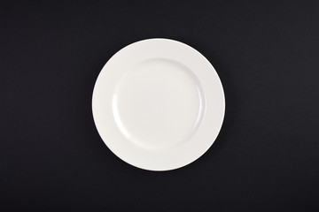 Top view of clean white dish on background of black table
