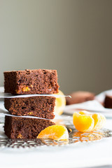 Homemade chocolate orange brownie. Stack three pieces. Dark Chocolate cake with orange. Light background. Vertical. Close up. Copy space