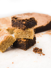 Stack of freshly baked brownies and snickerdoodle blondies squares on white baking parchment paper
