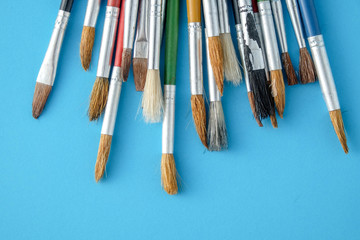 Fototapeta premium Row of artist paint brushes close up on blue background