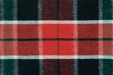 Soft and warm checkered wool blanket. Green and red plaid texture, macro shot. Wool plaid pattern. Textured surface of checkered cloth.