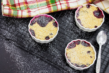 Two homemade mix berry oats crumble icing sugar in white ramekin. Healthy food concept. Selective focus