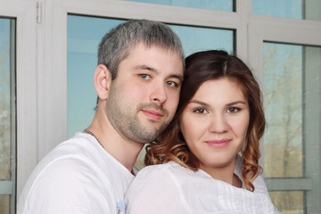 Happy woman and man in white t-shirt in room with big windows, close up