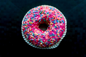 Pink donut with colorful sprinkles isolated on background