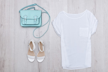 White top, white shoes and a mint bag. Fashionable concept. Wooden background