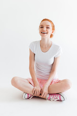 Vertical image of laughing ginger girl sitting on the floor