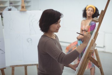 Female artist drawing a sketch of woman on canvas
