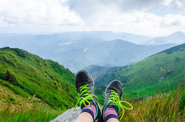Landscape, travel, tourism. Female feet in shoes on the background of mountains. Horizontal frame