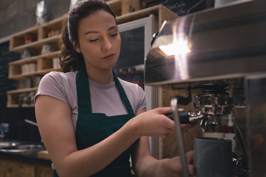 Waitress taking coffee from espresso machine