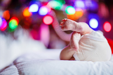 Naklejka premium newborn baby feet and diaper with Christmas tree and colorful garland lights