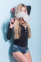 Close-up Portrait of sexy young hipster smoking (vaping) girl. Vapor concept. Vaping e-Cigarette.