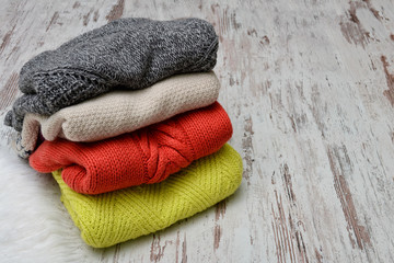Four warm sweaters on a wooden background. Fashion concept.