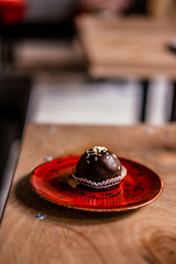 Vegan chocolate truffle on a red plate on a wooden table. Healthy raw energy bites
