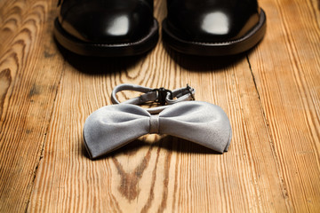 Zapatos negros y pajarita sobre un fondo de madera rústica. Vista de frente