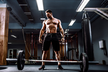 Muscular fitness man threw the bar on the floor after deadlift of a barbell in modern fitness...