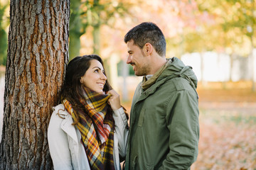 Lovely young couple flirting in autumn at the park. Romantic man and woman in love outdoor in fall season.