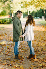 Lovely young couple flirting in autumn at the park. Romantic man and woman in love outdoor in fall season.