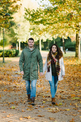 Naklejka na ściany i meble Lovely young couple walking together in autumn at the park.