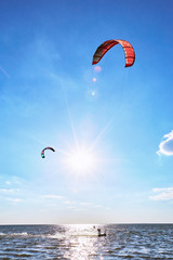 Man riding a kite surfing on the waves in the summer.