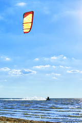 Man riding a kite surfing on the waves in the summer.