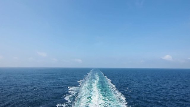 Ship wake on the ocean. Water foam trace behind the large ship goes till the horizon.