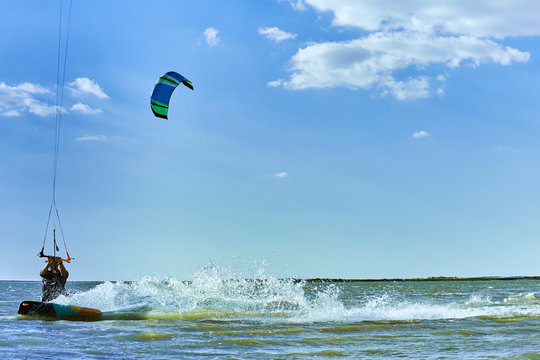 Man riding a kite surfing on the waves in the summer.