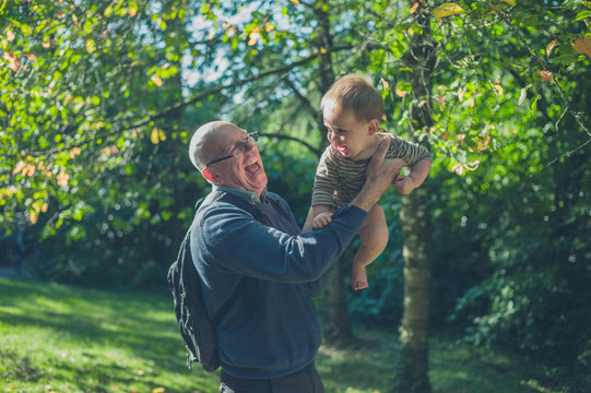 Senior man lifting baby grandson in nature