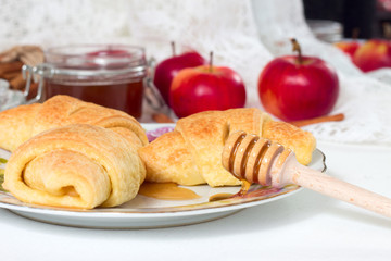 Freshly baked homemade sweet buns with apple seeds and honey on white table in saucer