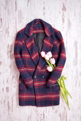 Warm checkered coats, tulips. Fashionable concept, top view, wooden background