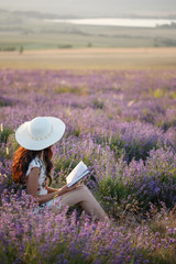 Fototapeta premium Romantic woman with book on lavender field