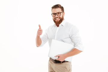 Handsome young bearded man holding laptop showing thumbs up.