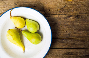 Green pears on rustic wooden background