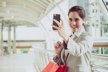 Business woman hold shopping bag and talk with freind by phone in city