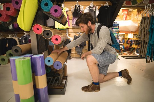 Man examining exercise mats in shop