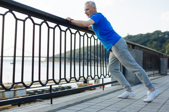 Athletic senior man doing stretching on the bridge