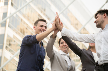 Businessman with colleagues hi five hand to cooperate on building background outdoor in city