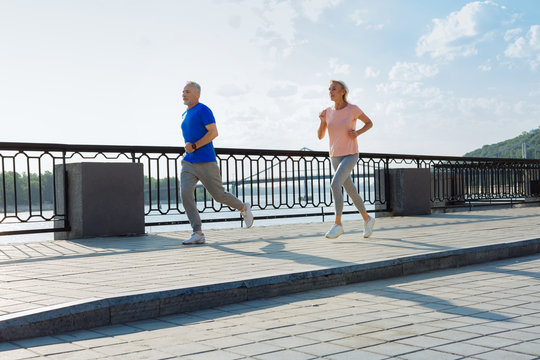 Fit senior couple running down the bridge