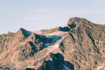 Sunset light over retiring dying glaciers on the Italian French Alps. Climate change concept. Toned desaturated image.