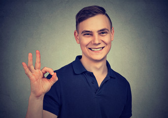 Handsome young man showing ok sign isolated on gray background