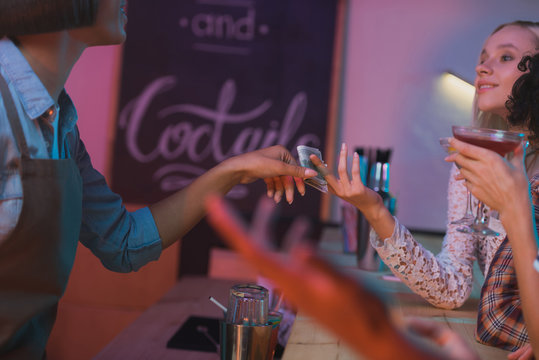 woman paying barman for cocktails