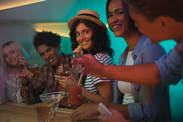 multiethnic friends drinking cocktails in bar